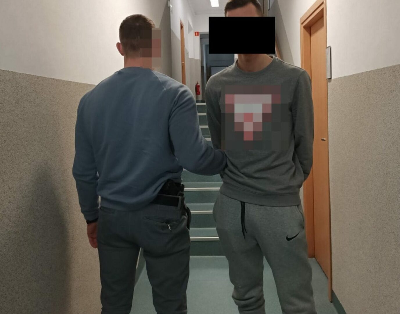 Policjant eskortujący podejrzanego korytarzem.