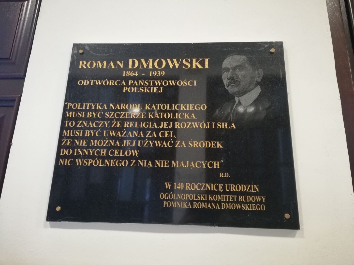 Tablica pamiątkowa upamiętniająca Romana Dmowskiego, polskiego męża stanu, z cytatem.