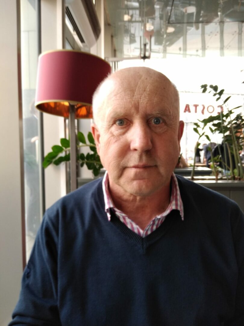 Portret dojrzałego mężczyzny z krótkimi, jasnosiwymi włosami.