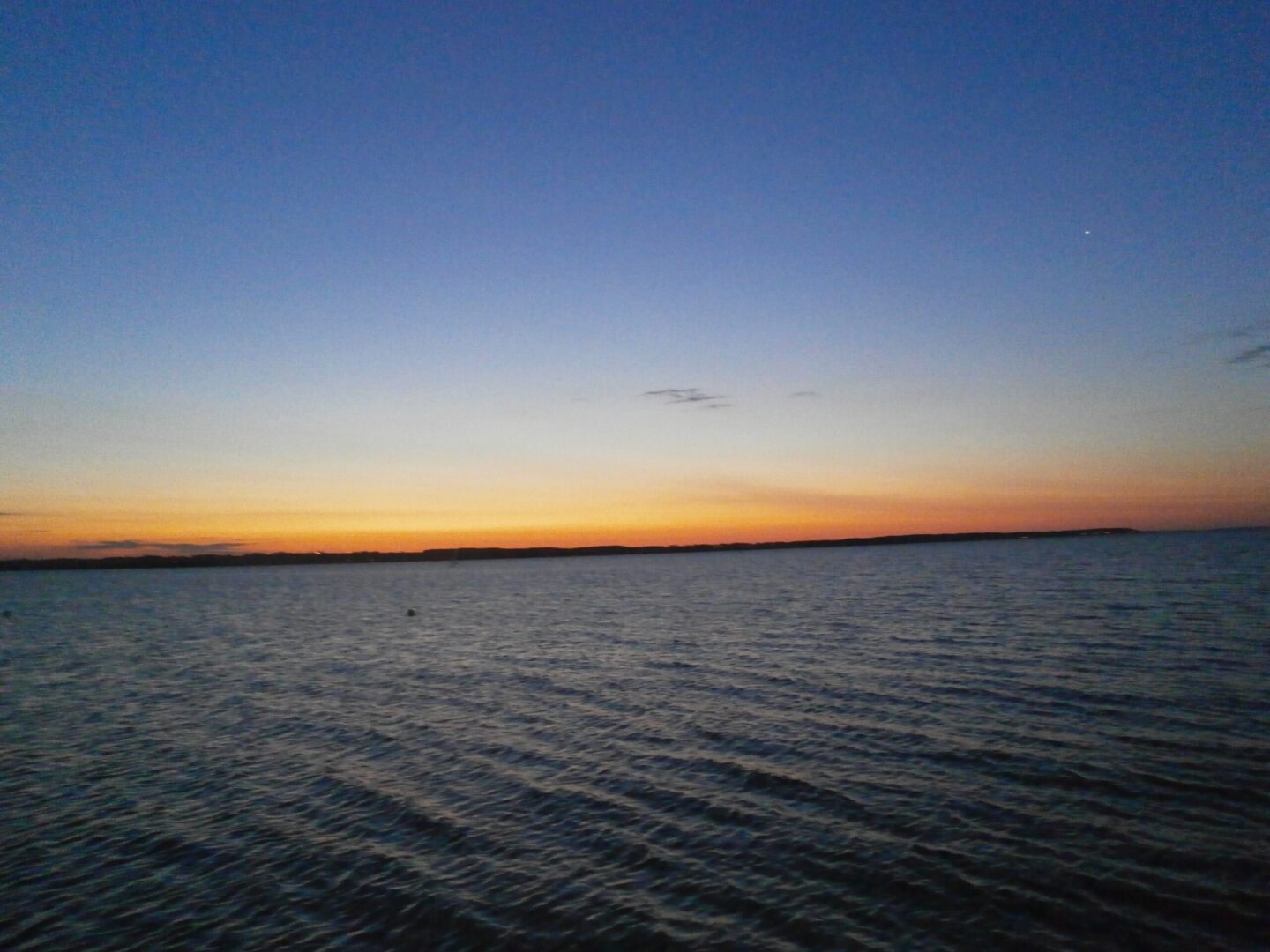 Spokojny zachód słońca nad spokojną wodą oceanu