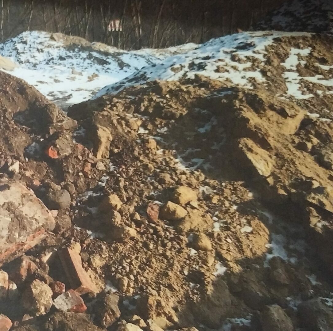 Stos gruzu i ziemi z łatami śniegu, prawdopodobnie plac budowy lub rozbiórki.