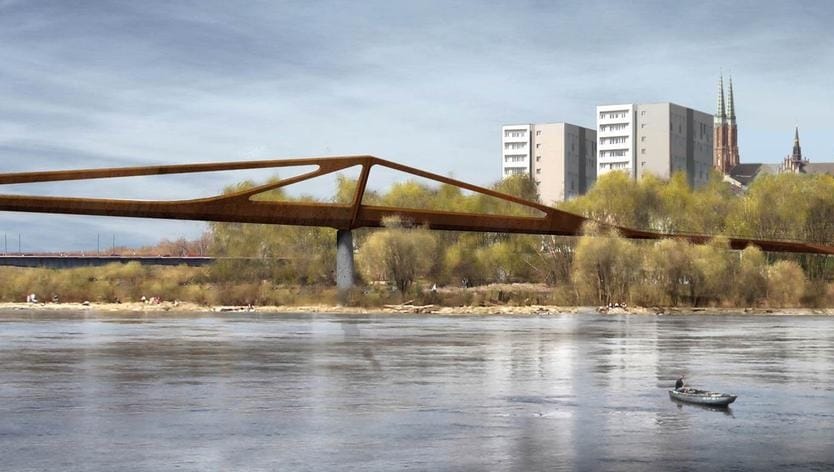 Smukła kładka dla pieszych nad rzeką, w tle nowoczesna architektura.