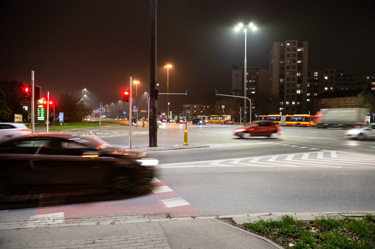 Nocne skrzyżowanie z samochodami i autobusami na światłach