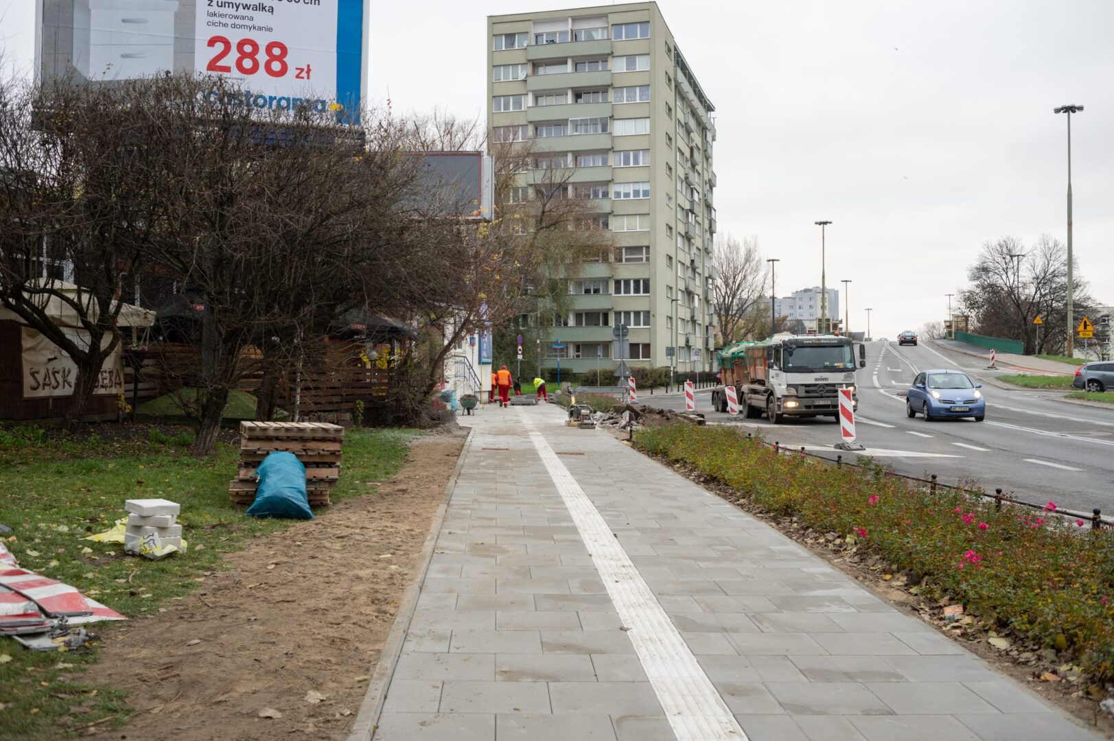 Ekipa budowlana pracująca nad nową nawierzchnią chodnika w ramach projektu odnowy miasta. 288 zł.