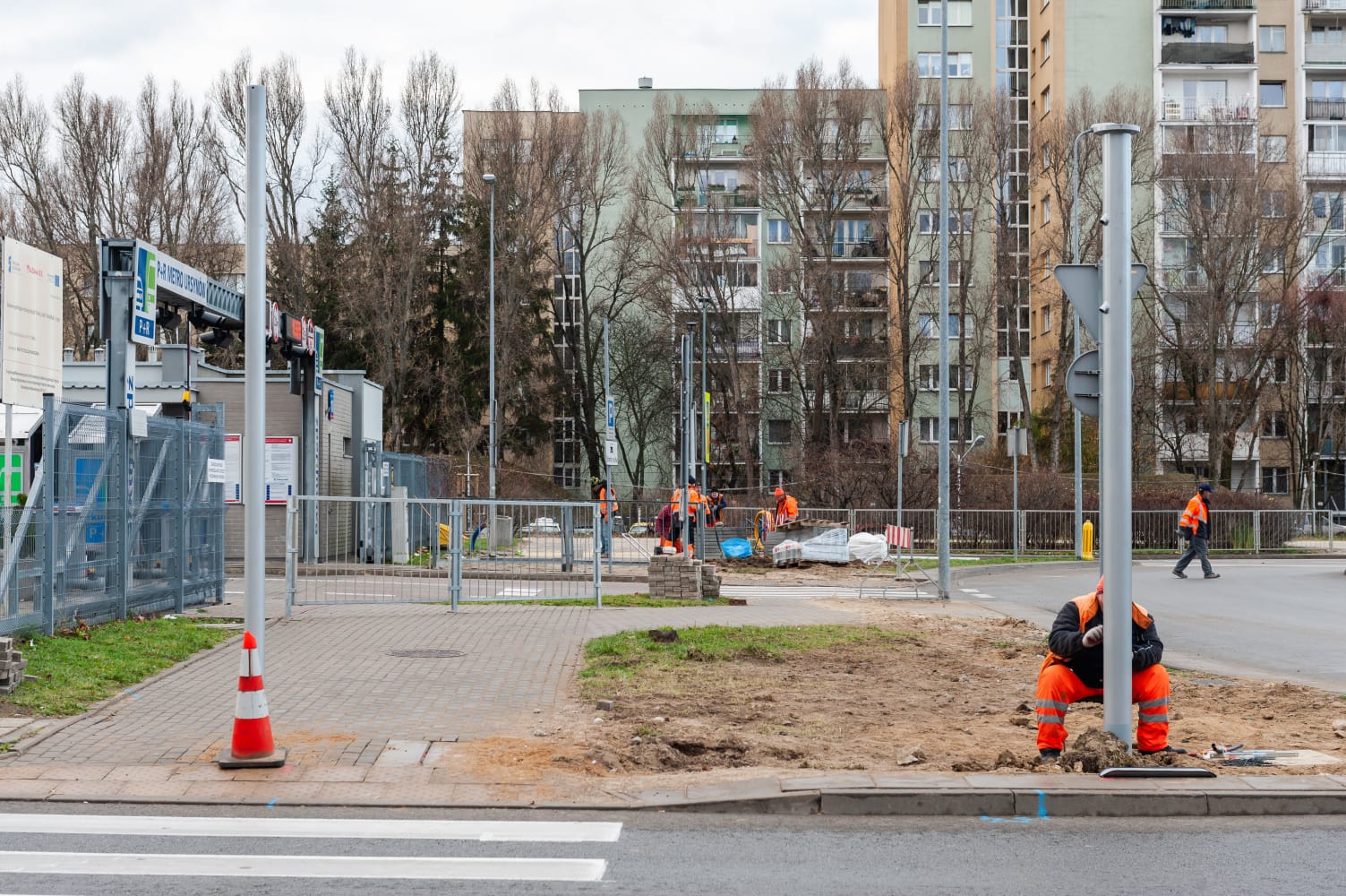Robotnicy budowlani montujący słupy energetyczne w pobliżu miejskiej ulicy.