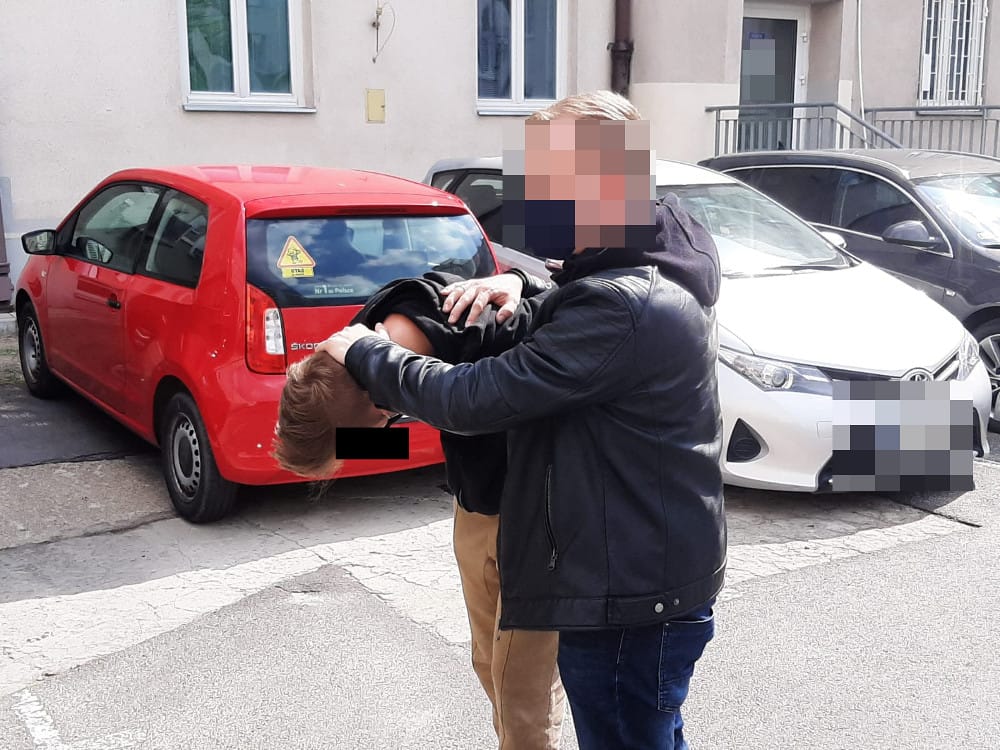 Policjant zatrzymuje podejrzanego na ulicy miasta.