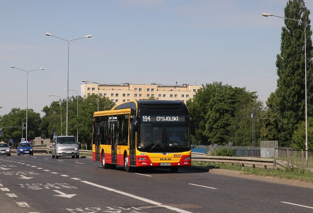 Żółto-czarny autobus miejski numer 194 jedzie ulicą miasta.