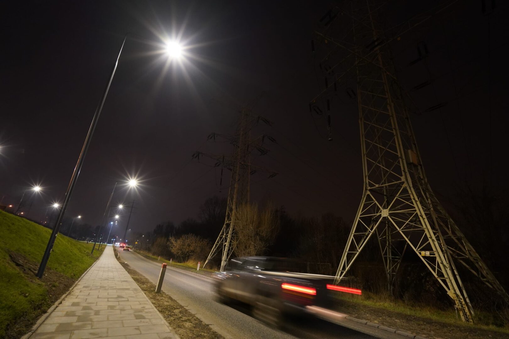 Nocny widok drogi z nowymi latarniami ulicznymi na Pradze, w pobliżu linii energetycznych.