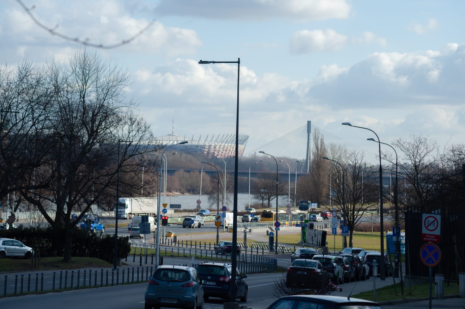 Widok na warszawską ulicę z nowymi latarniami na ulicach Konwiktorskiej i Sanguszki. W tle widać most i stadion.