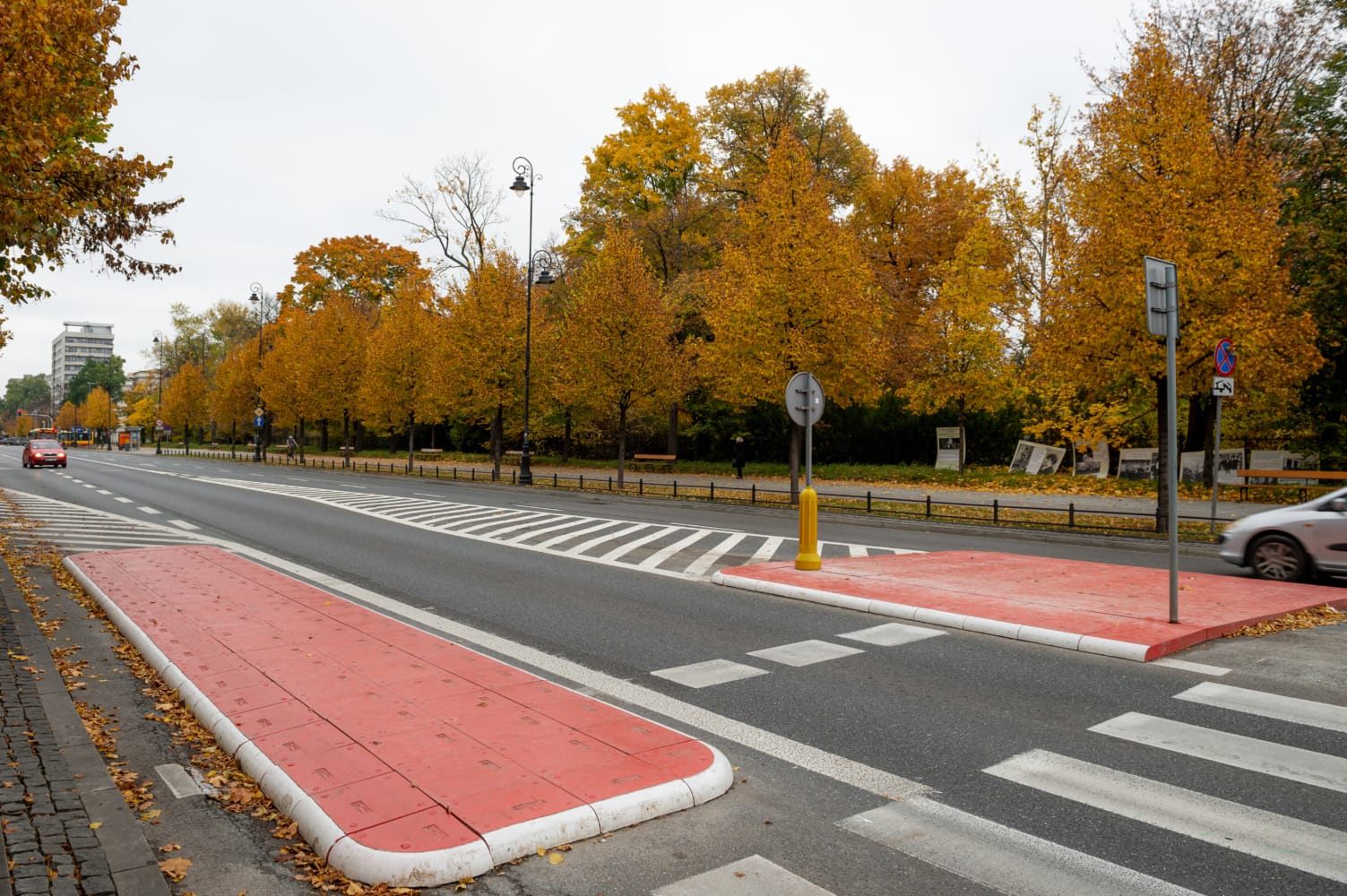 Jesienna ulica miejska z przejściem dla pieszych i czerwoną, dotykową nawierzchnią
