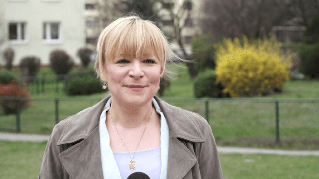 Uśmiechnięta blondynka ubrana w szarą kurtkę