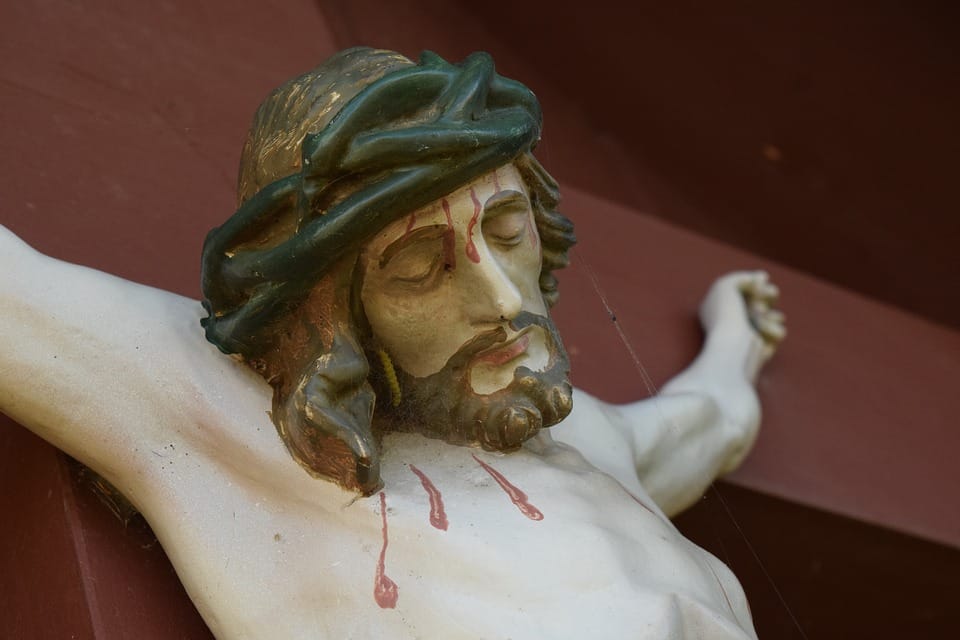 Zbliżenie zniszczonego krucyfiksu przedstawiającego Jezusa Chrystusa w koronie cierniowej.