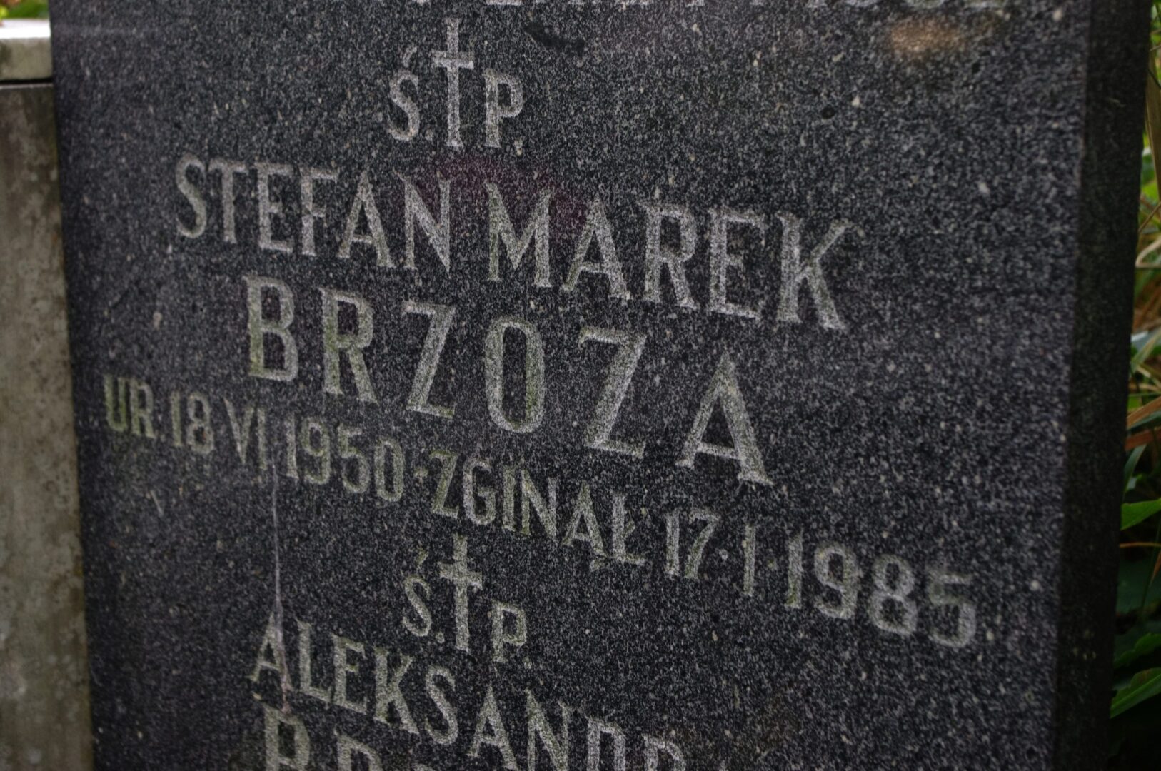 Zbliżenie zniszczonego napisu na nagrobku: ŠTP. Štefan Marek Brzoza, ur. 18.VII.1950, zginal 17.I.1985. ŠTP. Aleksander...