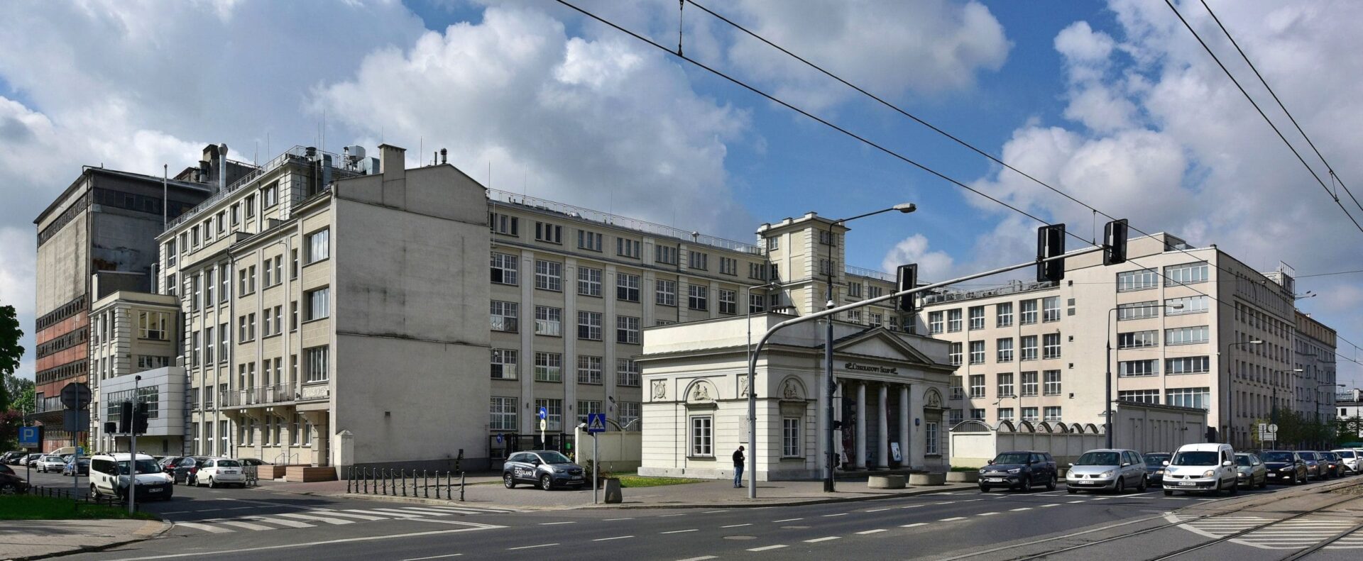 Nowoczesny kompleks budynków w Warszawie, charakteryzujący się klasycystyczną bramą wjazdową.