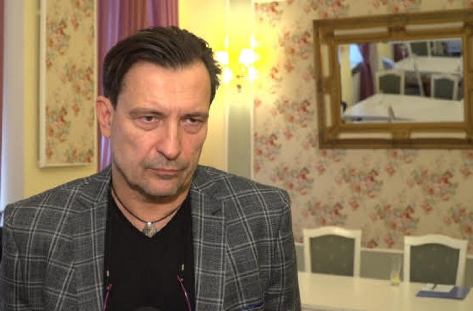 Mężczyzna w szarej kraciastej kurtce, poważny wyraz twarzy