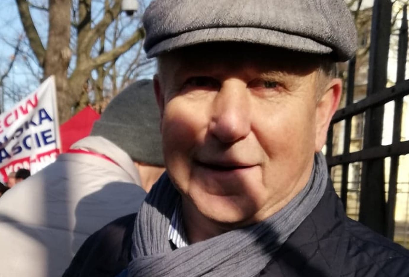 Starszy mężczyzna w czapce z daszkiem podczas protestu.