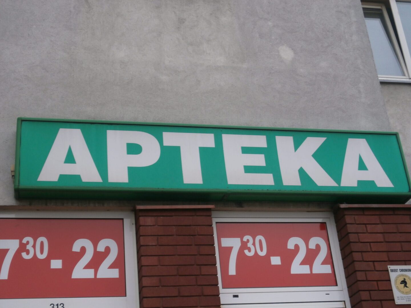 Tablica informacyjna apteki Apteka Bliska z godzinami otwarcia 7:30-22. Dostawa dostosowana do potrzeb seniorów.