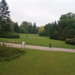 Spokojny park ze ścieżkami spacerowymi, ławkami i bujną zielenią.