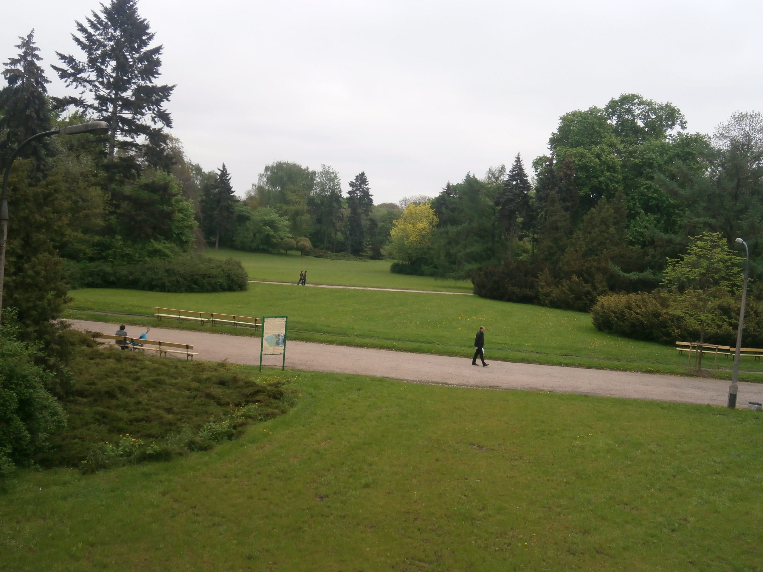 Spokojny park ze ścieżkami spacerowymi, ławkami i bujną zielenią.