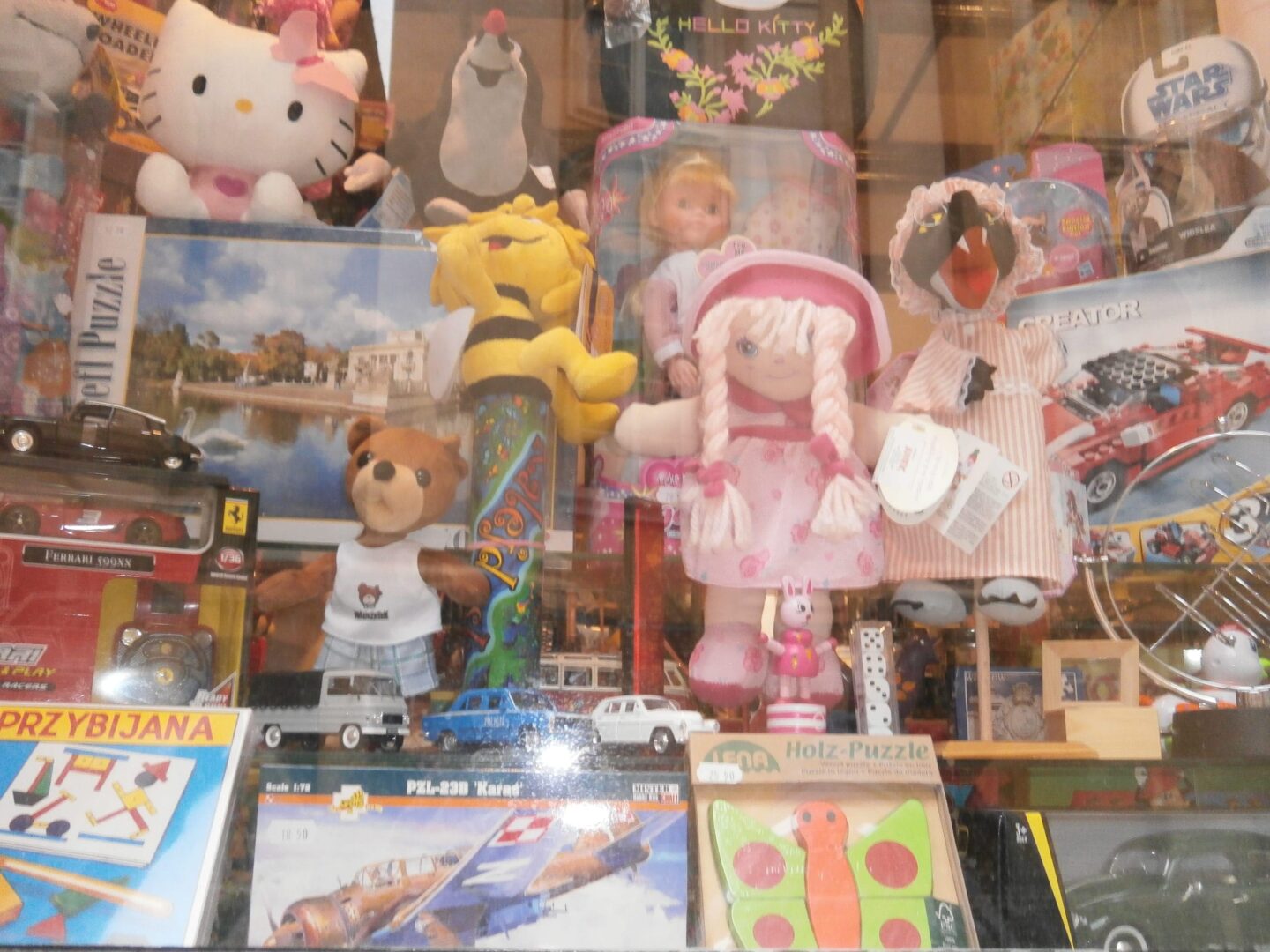Asortyment zabawek i puzzli na wystawie sklepowej, w tym Hello Kitty, misie i drewniane puzzle.