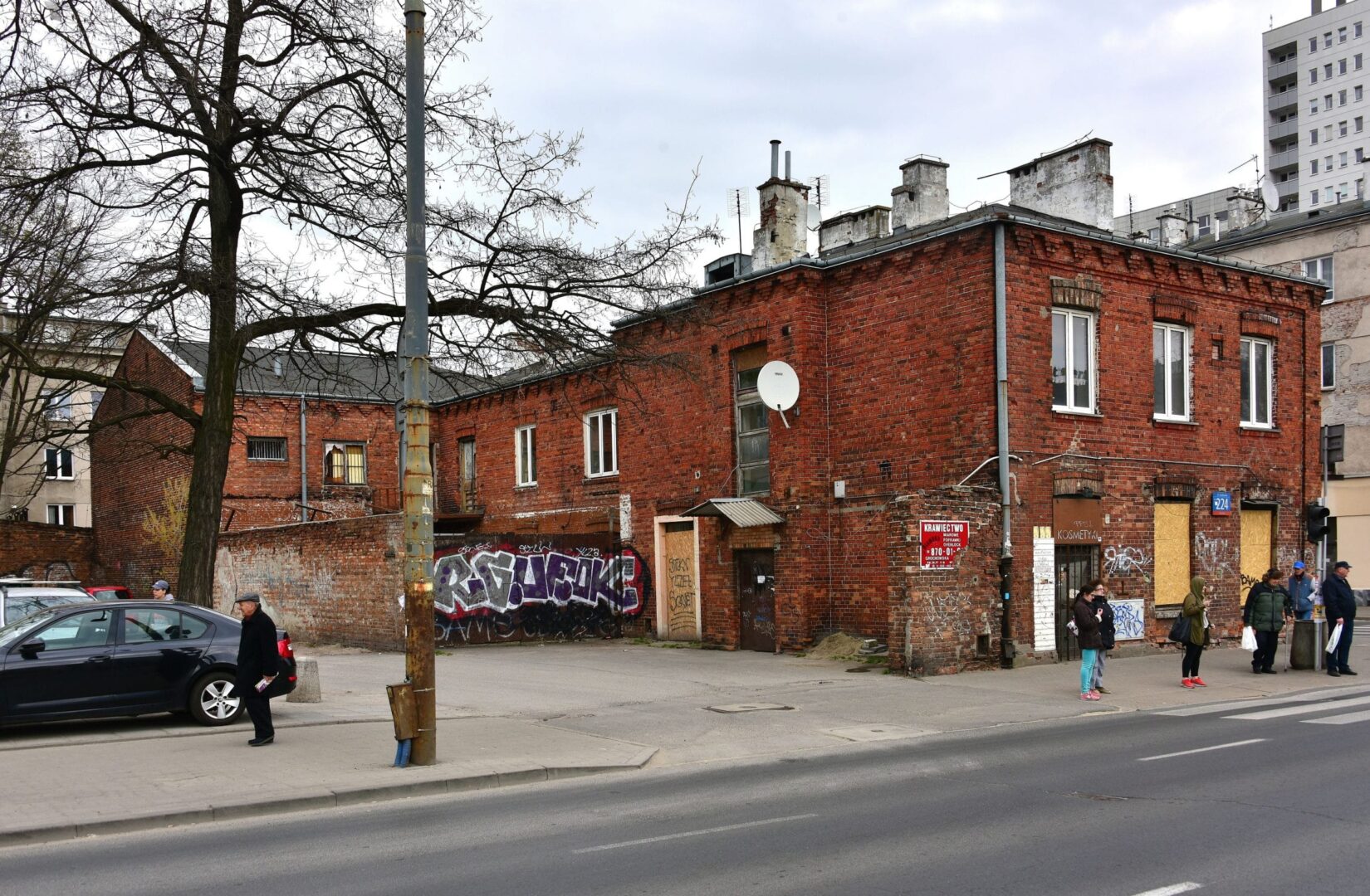Stary ceglany budynek na Grochowie w Warszawie, przeznaczony do rozbiórki. Widoczny napis „Krawiectwo”.