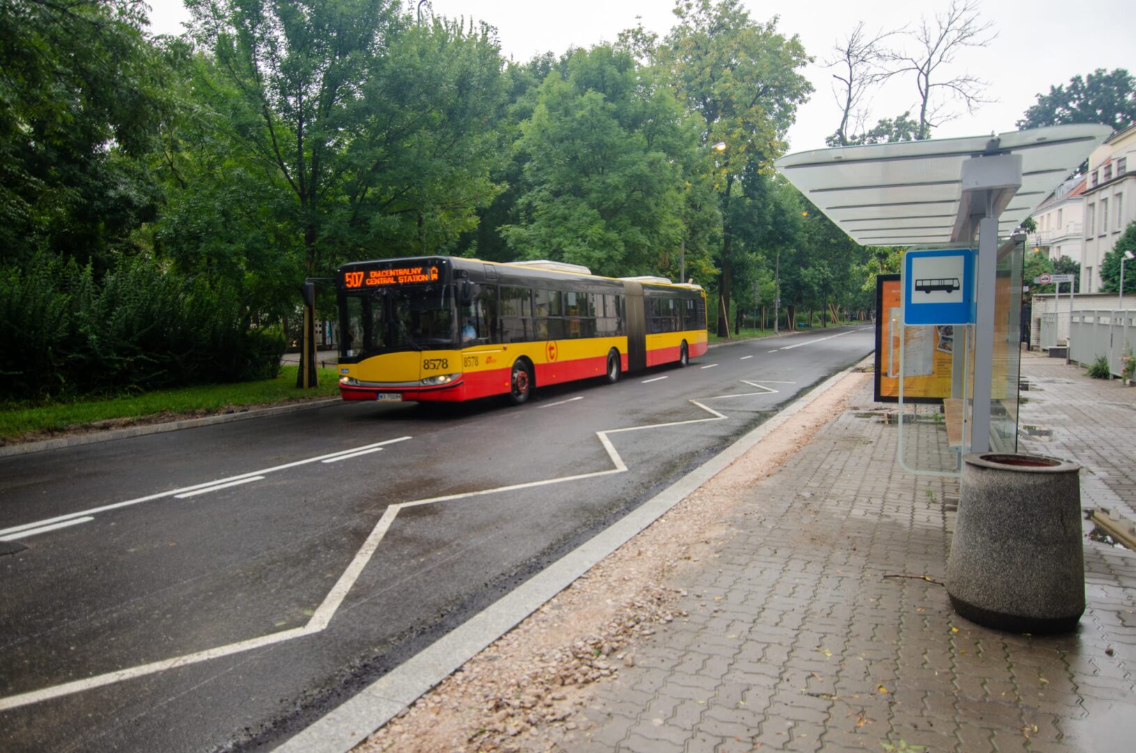 Żółto-czarny autobus miejski nr 507 jadący w kierunku Dworca Centralnego zatrzymuje się na nowoczesnym przystanku autobusowym.