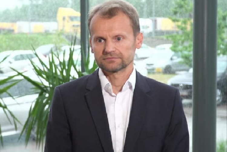 Portret mężczyzny w ciemnym garniturze, wyglądającego poważnie.