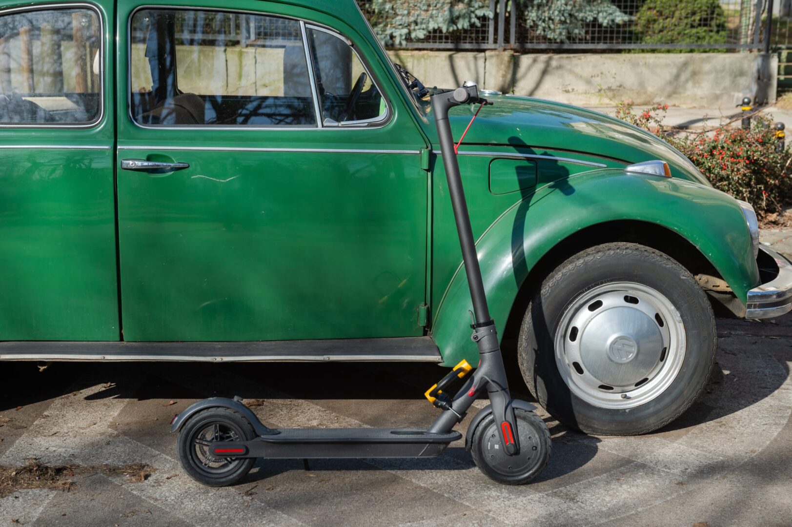 Elektryczny skuter zaparkowany obok zabytkowego zielonego Volkswagena Garbusa.