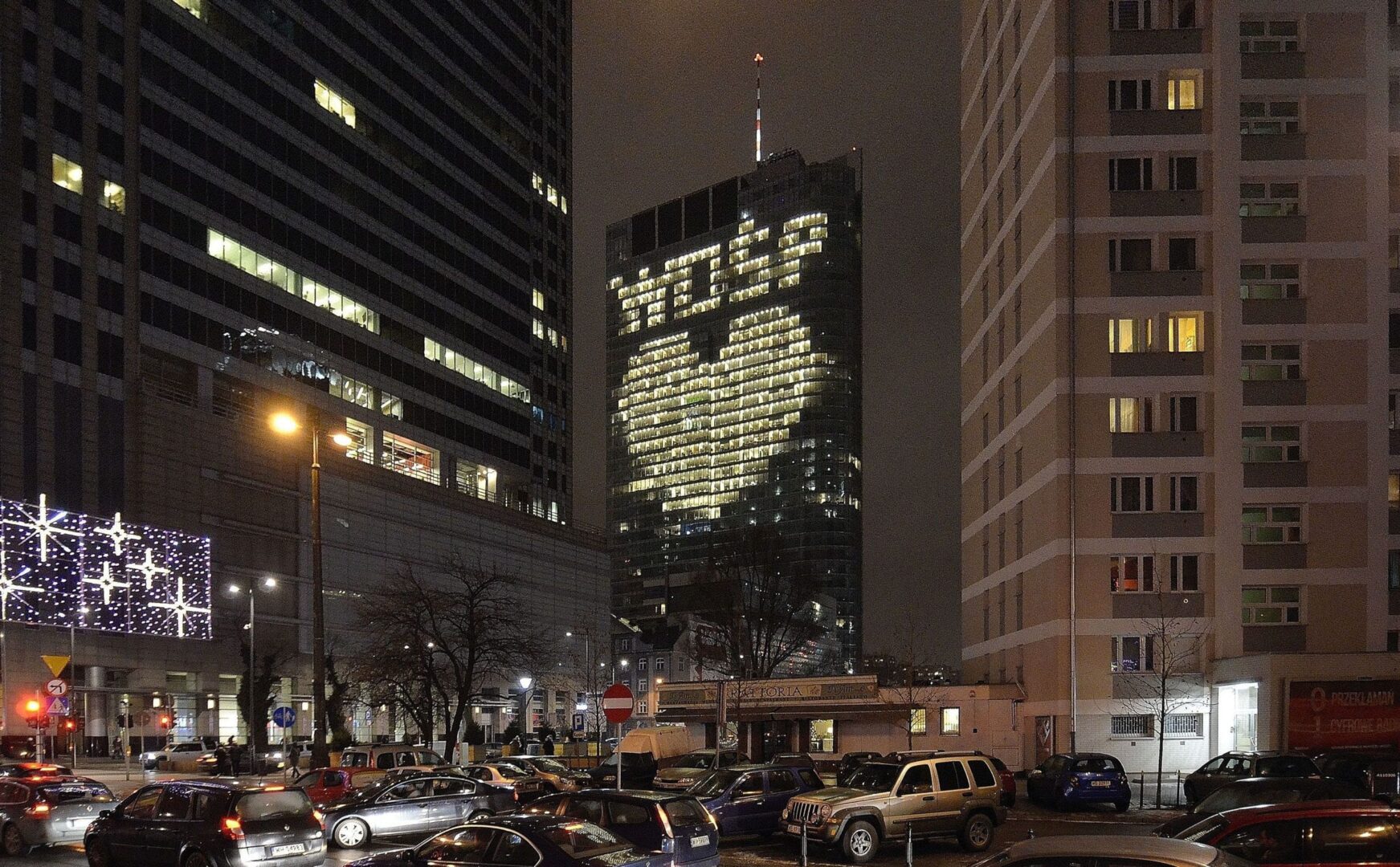 Warszawski wieżowiec Złota 44 nocą, oświetlony napisem „Happy Peace”.