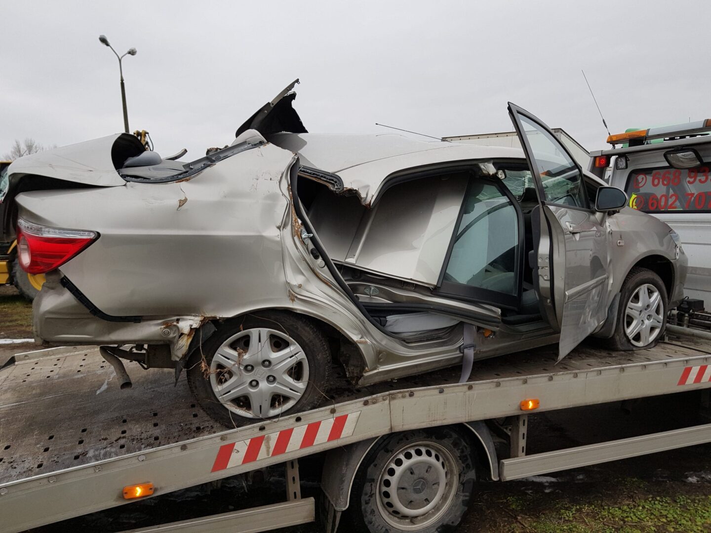 Silnie uszkodzony srebrny Honda Civic na lawecie. Uszkodzenia po wypadku samochodowym.