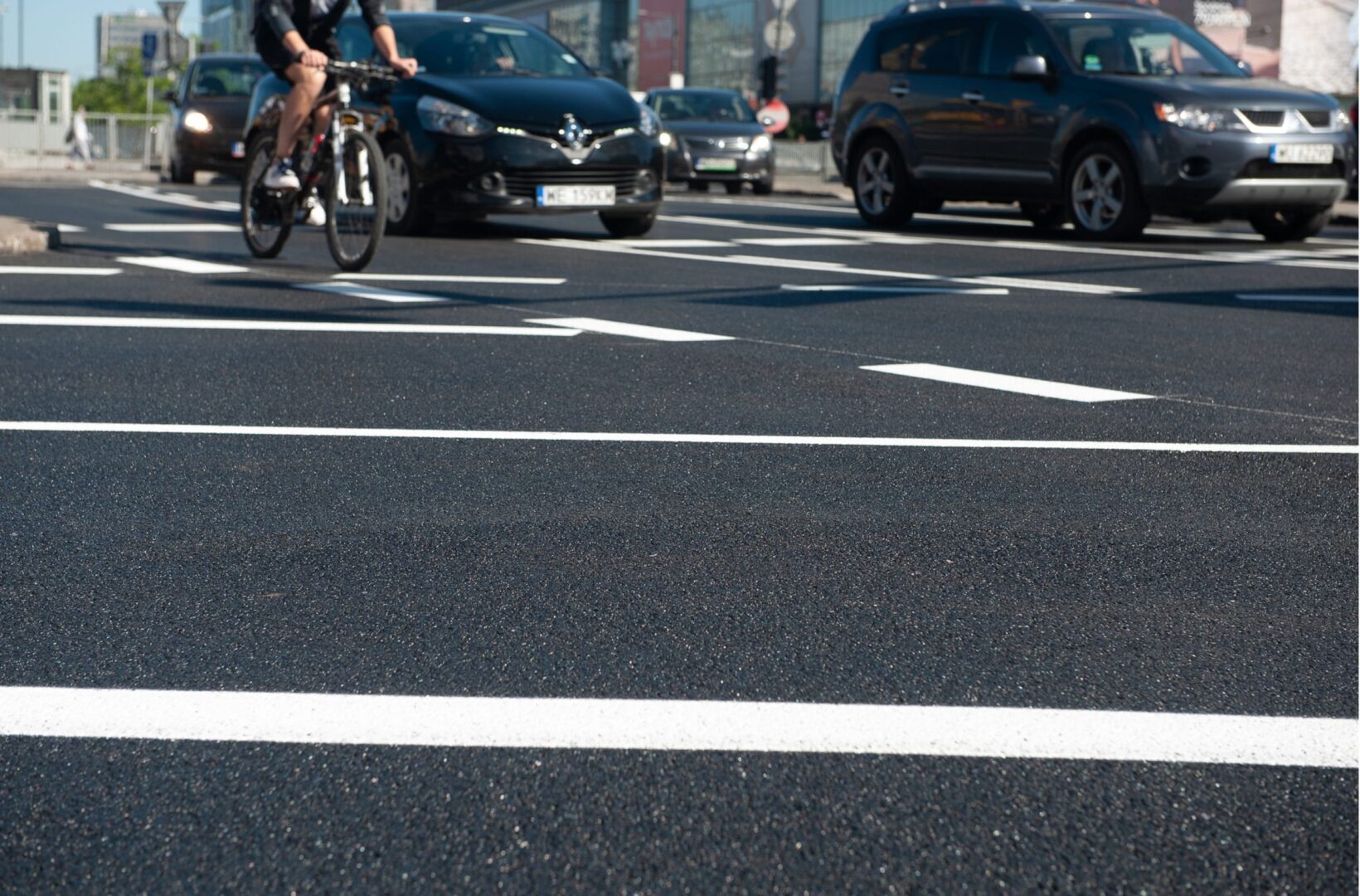 Rowerzysta jadący ulicą miasta, na której są samochody, ilustruje jazdę na rowerze w mieście w czasach spokoju.