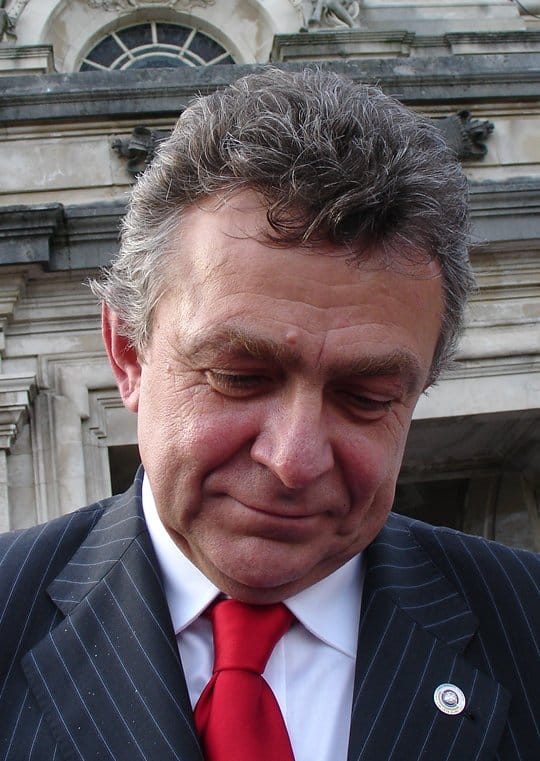 Portret mężczyzny w garniturze w prążki i czerwonym krawacie.