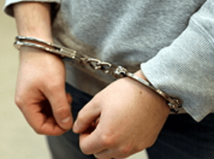 Zbliżenie dłoni skutych kajdankami.