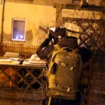 Policjant celujący z karabinu w czasie nocnej operacji.