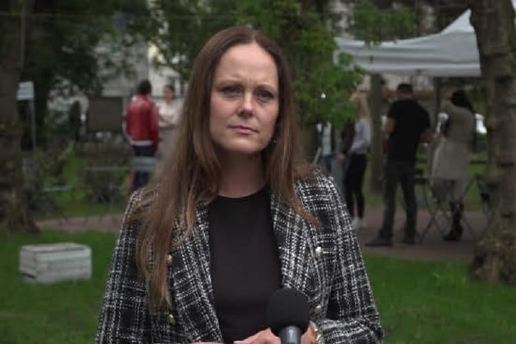 Kobieta w tweedowej kurtce mówi do mikrofonu podczas wywiadu