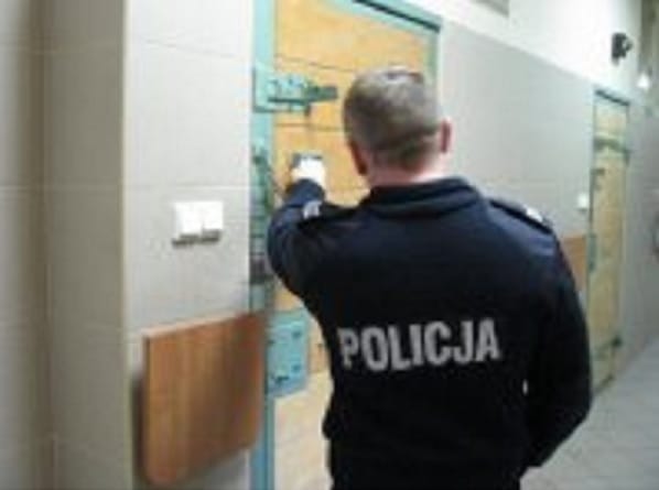 Policjant otwierający drzwi celi więziennej