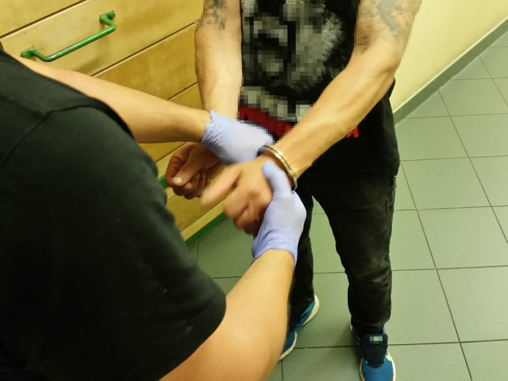 Policjant zakładający podejrzanemu kajdanki podczas aresztowania.