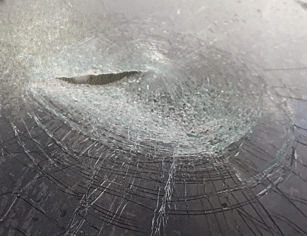 Zbliżenie pękniętej szyby samochodu z dużym punktem uderzenia.