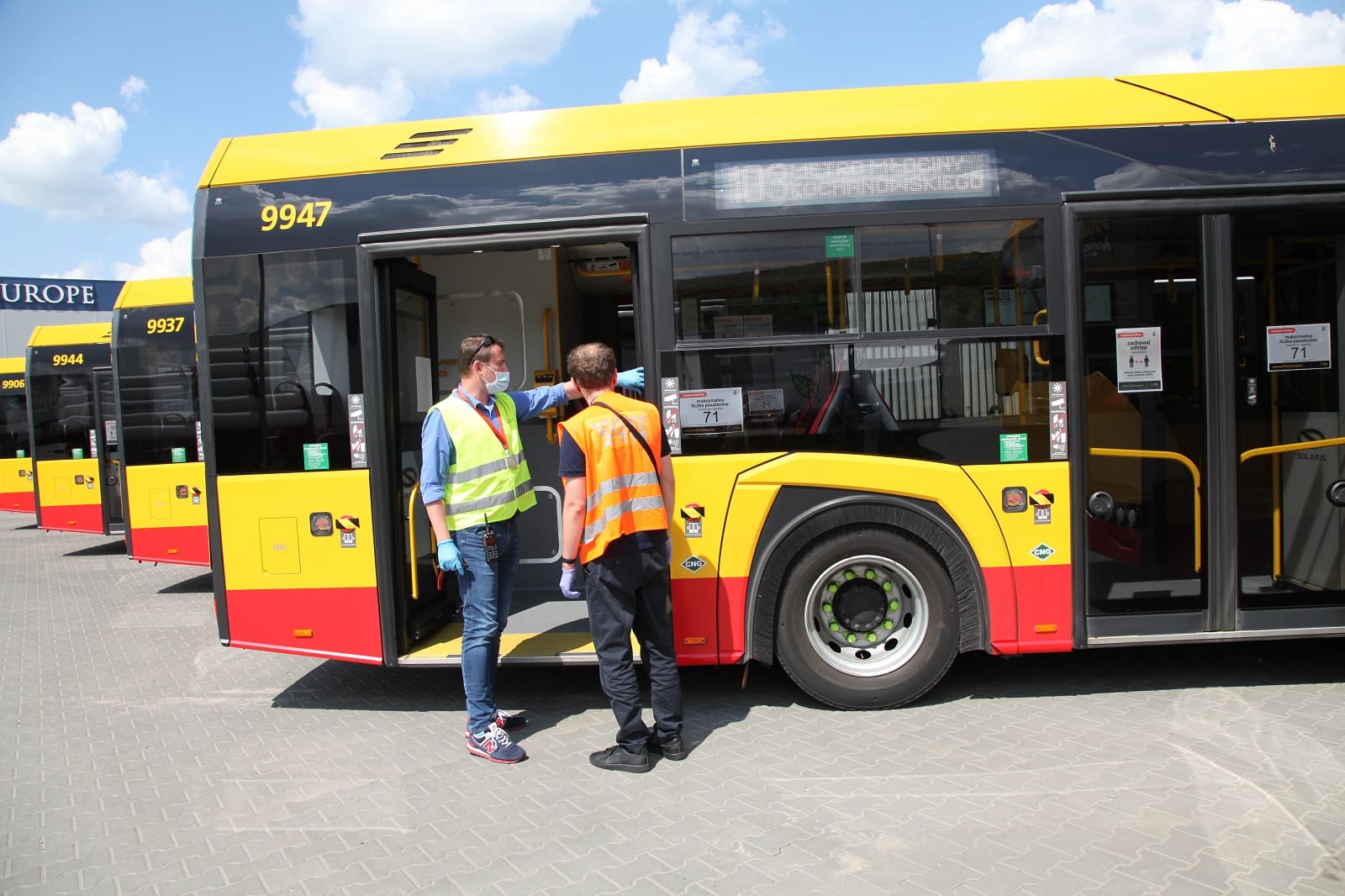 Dwóch pracowników transportu publicznego w maskach ochronnych ogląda nowy autobus Solaris Urbino CNG nr 9947.