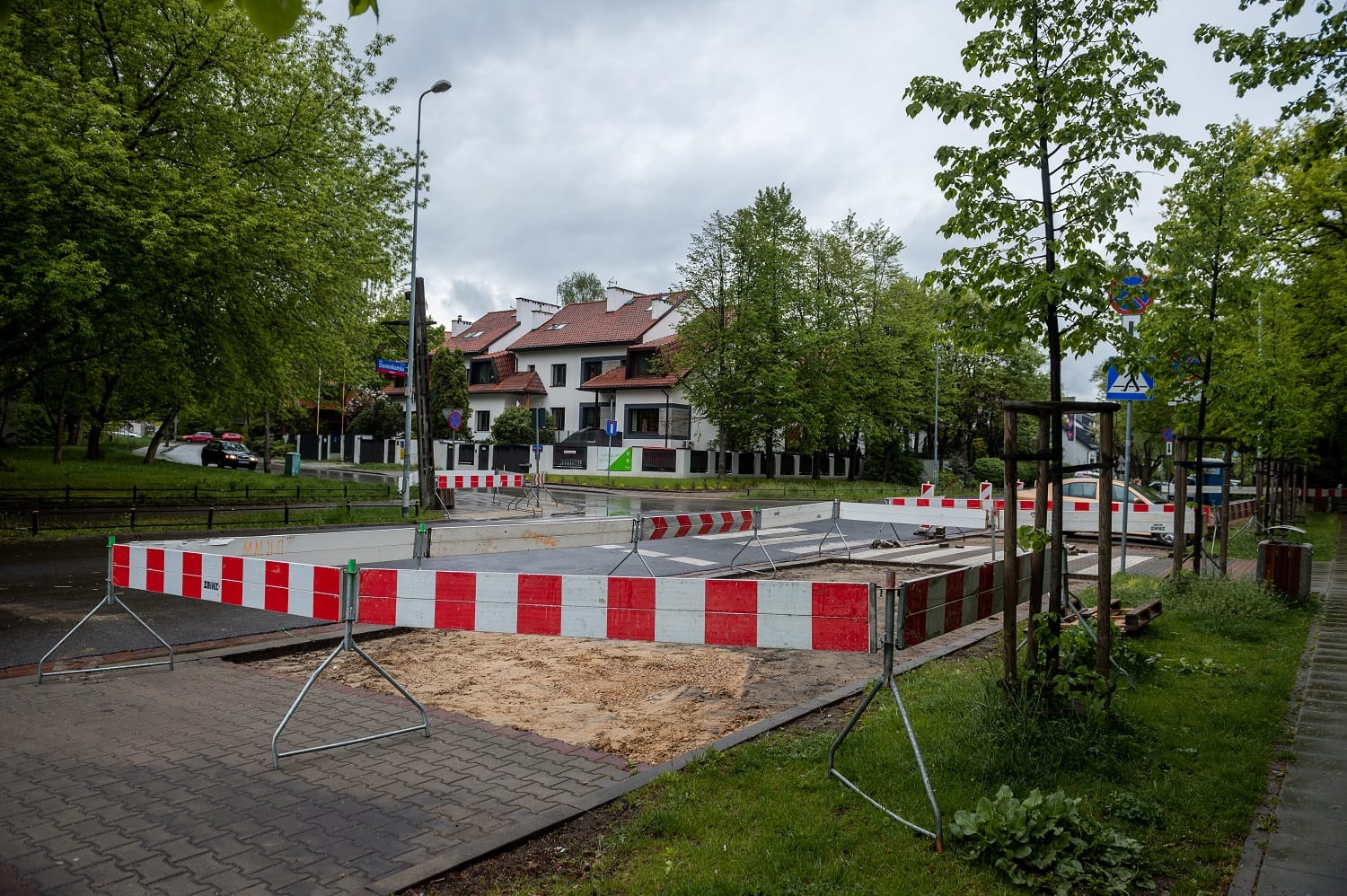 Plac budowy drogi z czerwonymi i białymi barierami blokującymi część jezdni.