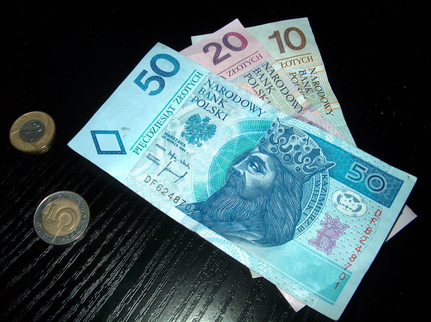 Banknoty i monety złote polskie (50, 20, 10).