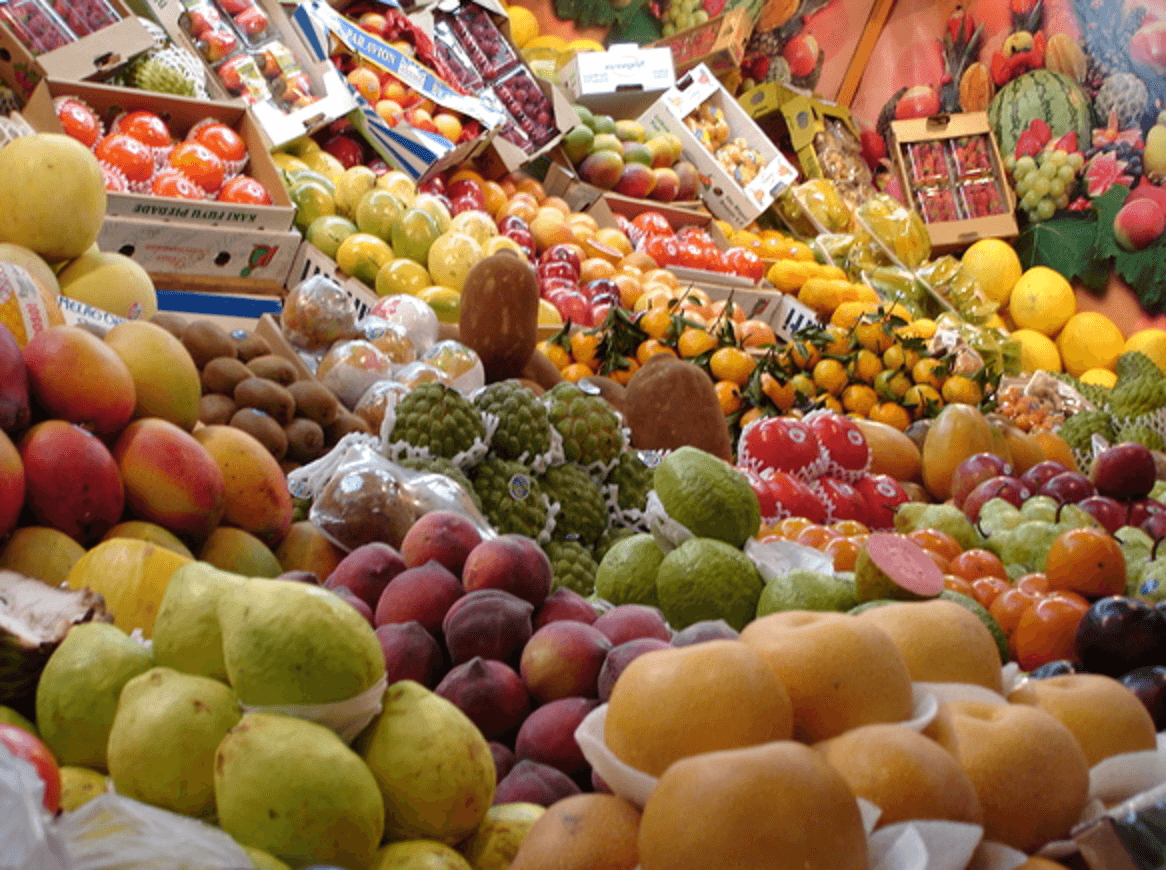 Mnóstwo kolorowych owoców i warzyw na tętniącym życiem straganie na targu.