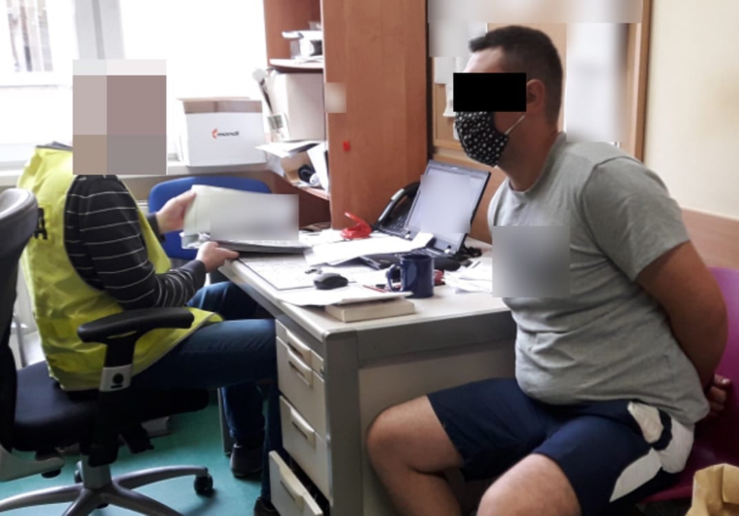 Przesłuchanie przez policję: Podejrzany w areszcie, przegląda dokumenty z funkcjonariuszem.