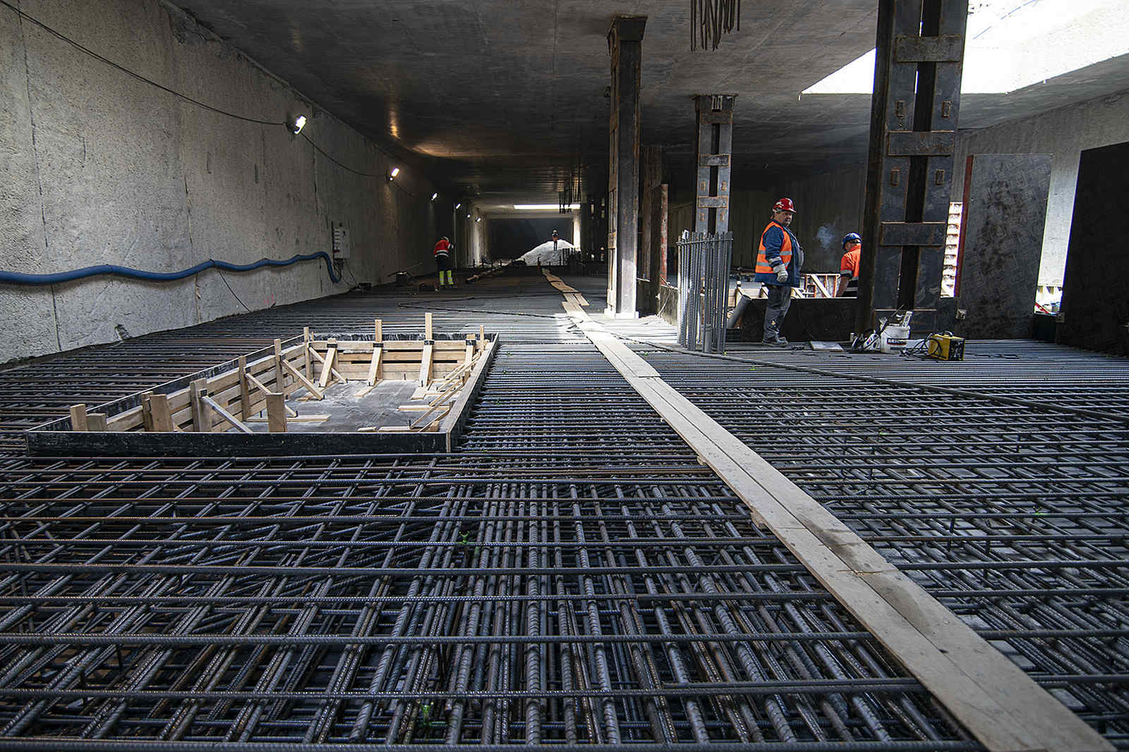 Pręty zbrojeniowe i drewniane szalunki przygotowane do wylewania betonu na placu budowy tunelu.