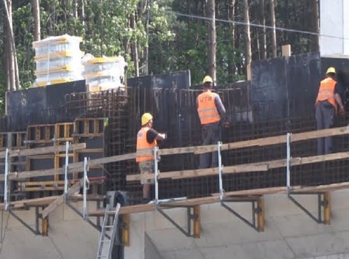 Robotnicy budowlani montujący szalunki ścienne z betonu na placu budowy.