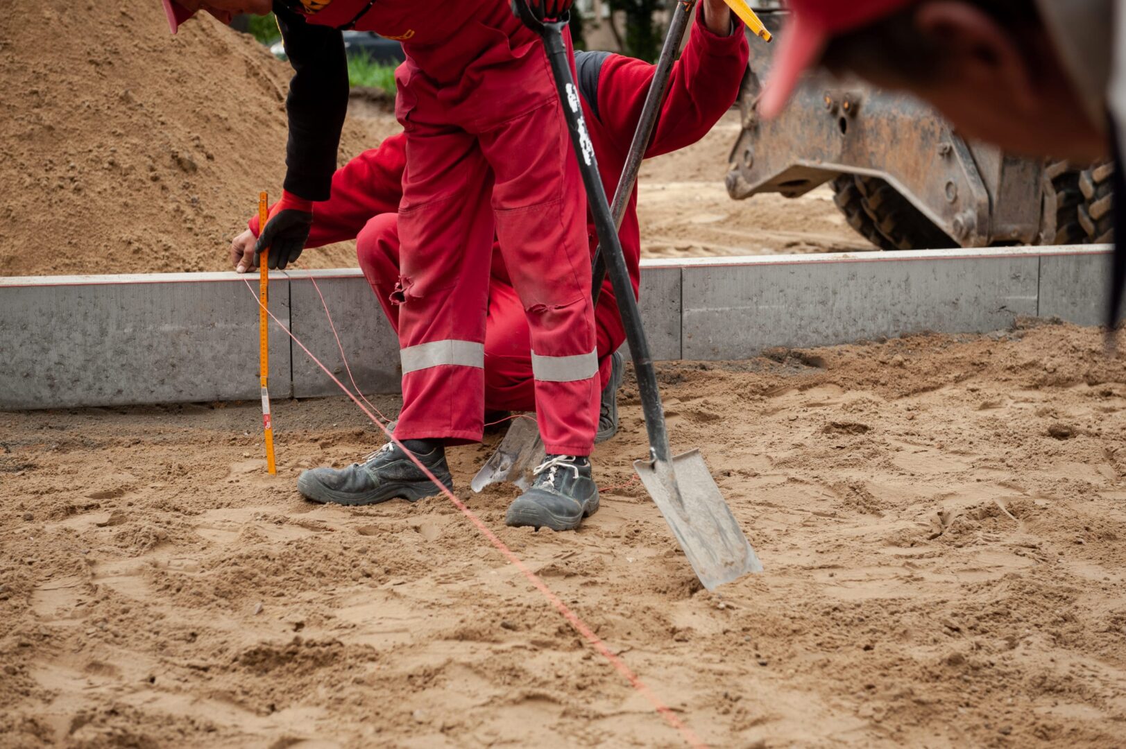 Robotnicy budowlani używają poziomicy i łopaty, aby przygotować grunt pod nowe rondo w Wawers.