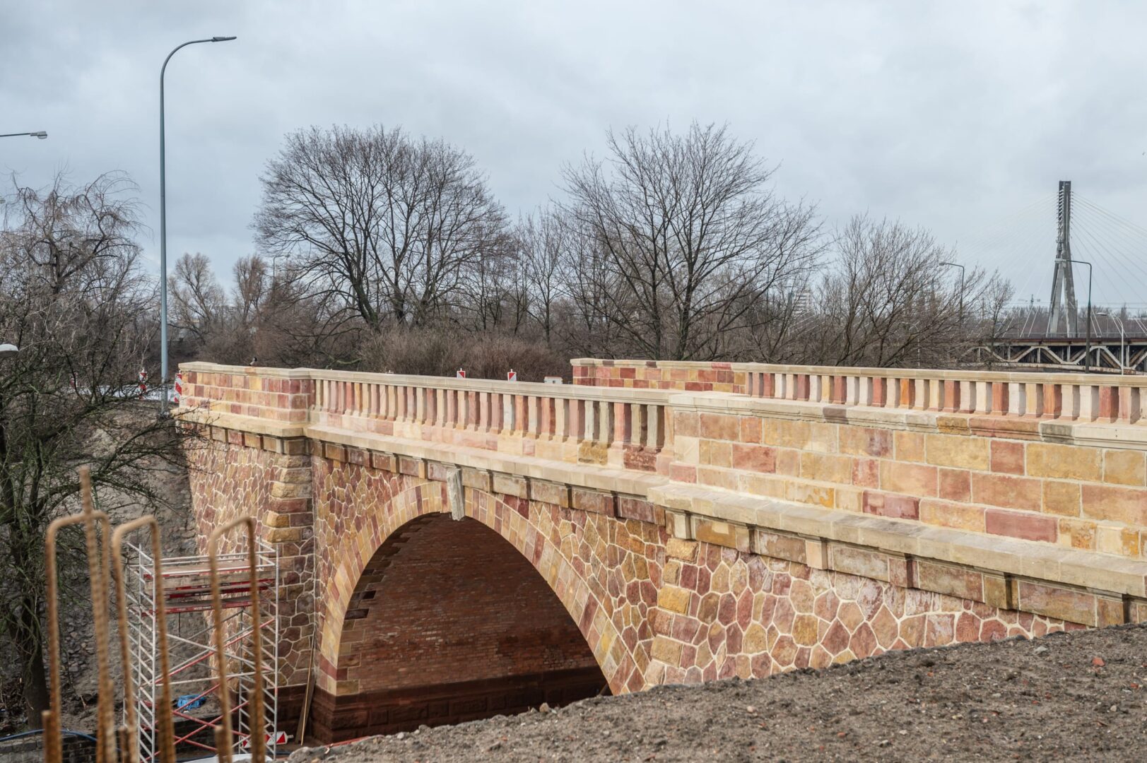 Odnowiony kamienny most z ceglanym łukiem, w trakcie budowy.