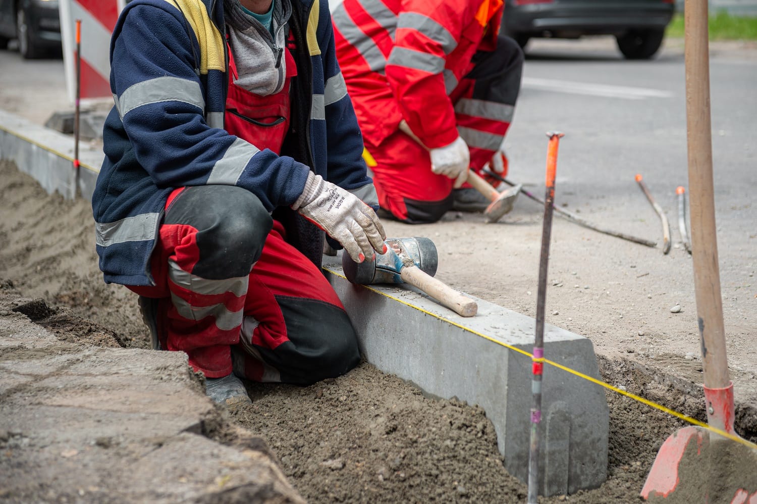Robotnicy budowlani montujący krawężniki przy użyciu narzędzi ręcznych