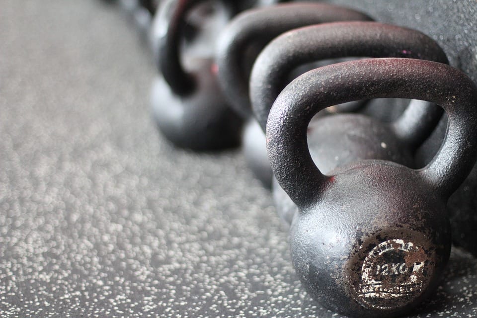 Rząd 12-kilogramowych odważników kettlebell na podłodze siłowni