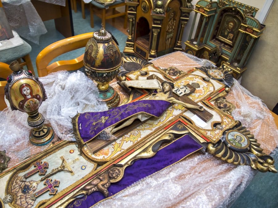 Ornate religious artifacts, including a crucifix and icons, displayed on a table. Bezcenne dzieła sztuki sakralnej.